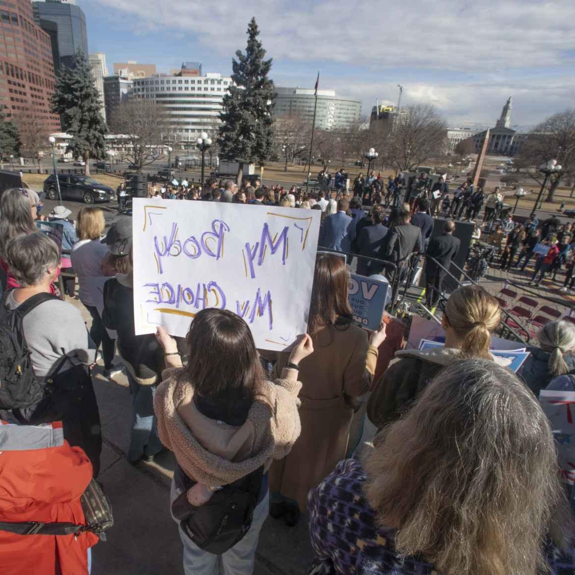 抗议者在人群中的照片，其中一人举着一个标语，上面写着“我的身体我的选择”